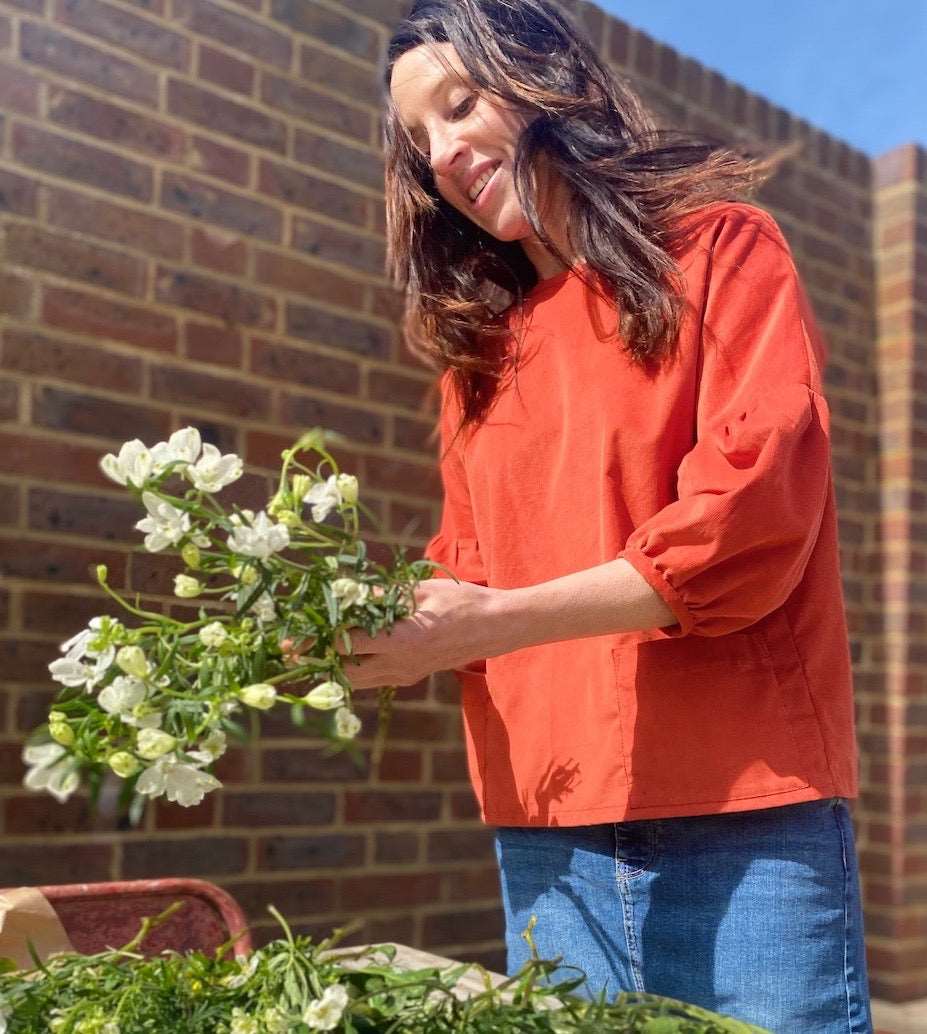 girl in a terracotta needlecord cloud blouse flower arranging