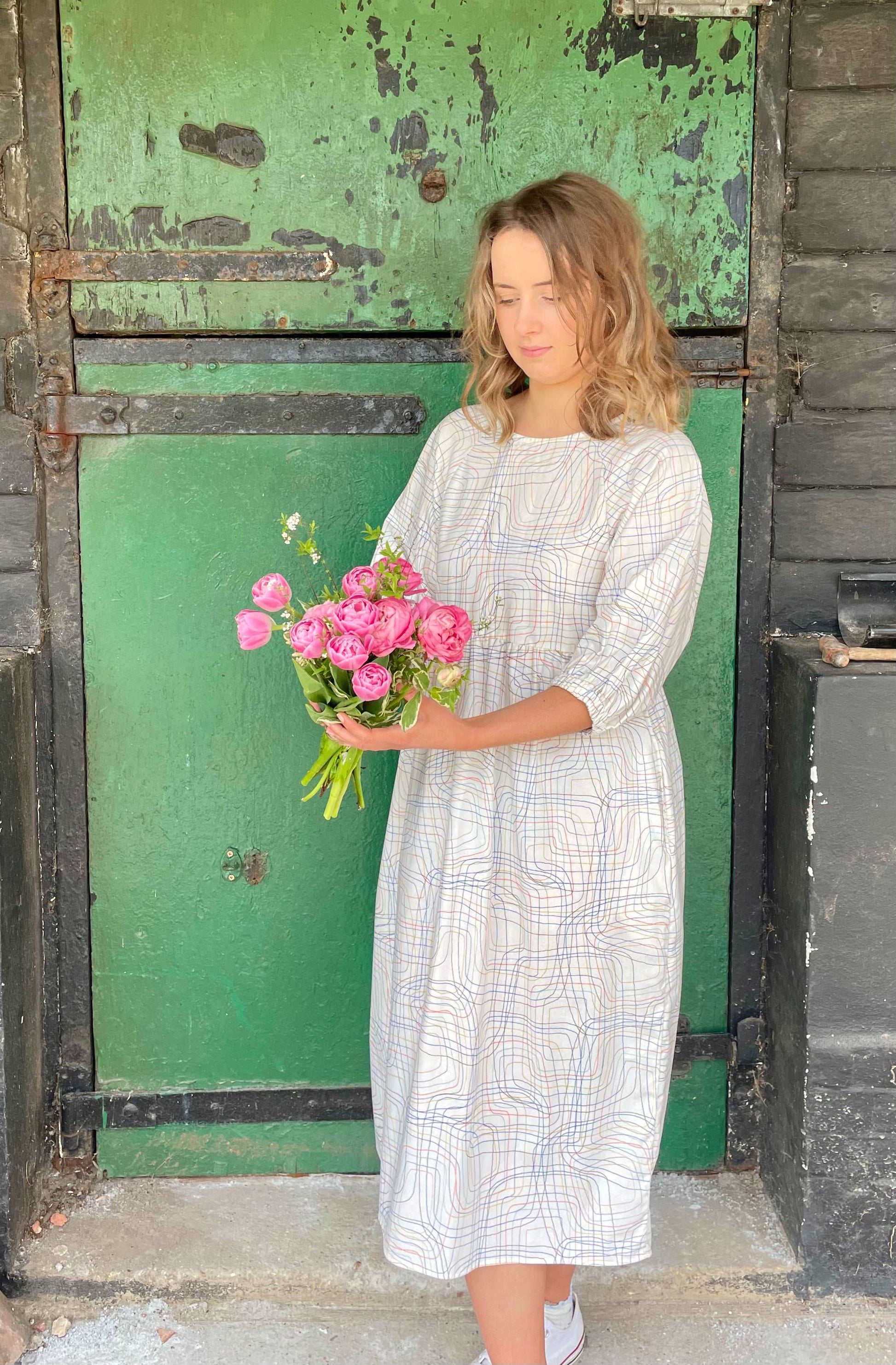 model wearing cream line patterned dress holding flowers