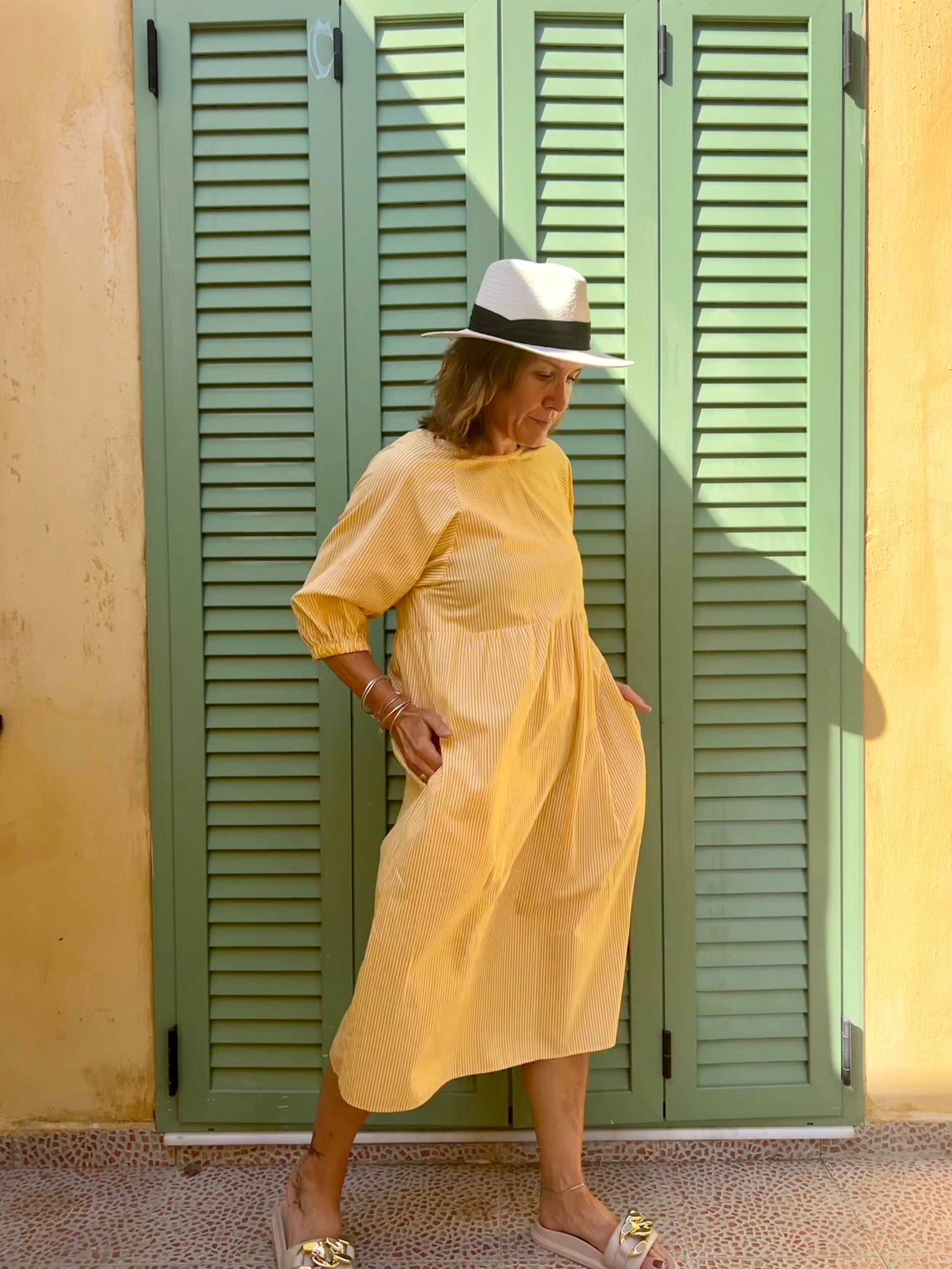 Model in yellow stripe dress wearing a Panama hat