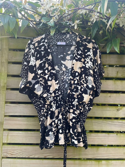 Angel tie front top in neutral print fabric on a hanger